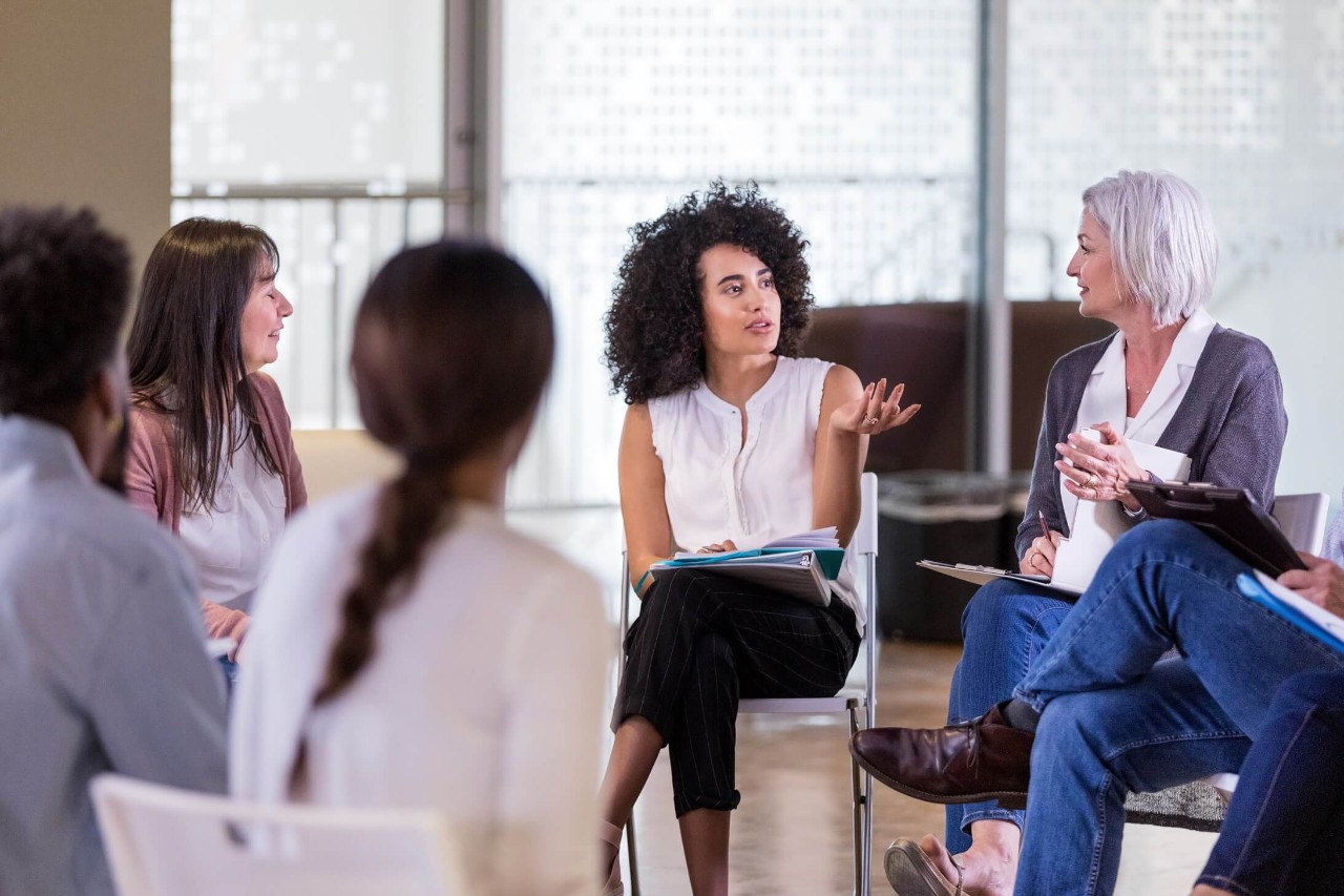 A group of colleagues sit together in a circle, conversing