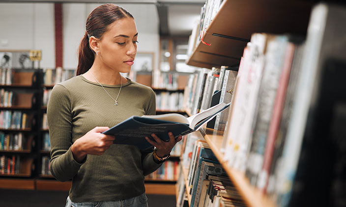 A researcher browses books in a library