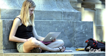 A university of phoenix student sitting on the ground, researching smart borrowing on their laptop