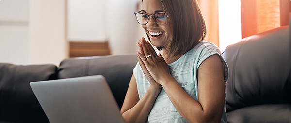 picture of a person smiling and placing their hands together while looking at their laptop