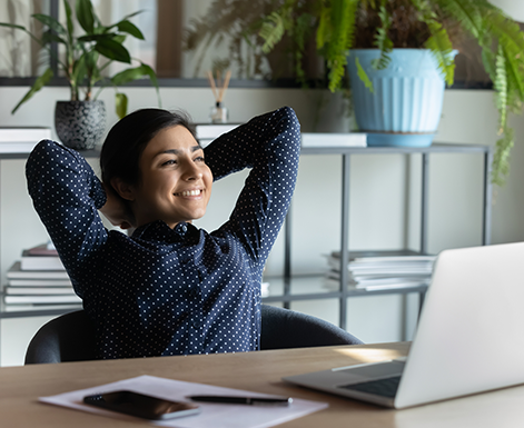 Woman relaxes, smiling while working on her laptop