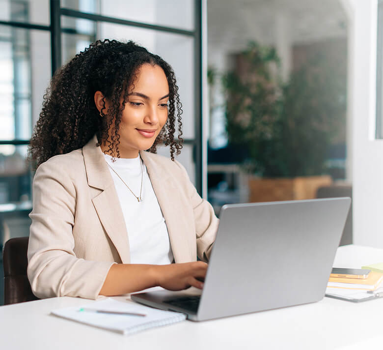 A woman works at her laptop in an office setting.