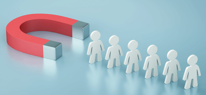 A magnet attracting a line of wooden cutouts of people to signify employee retention